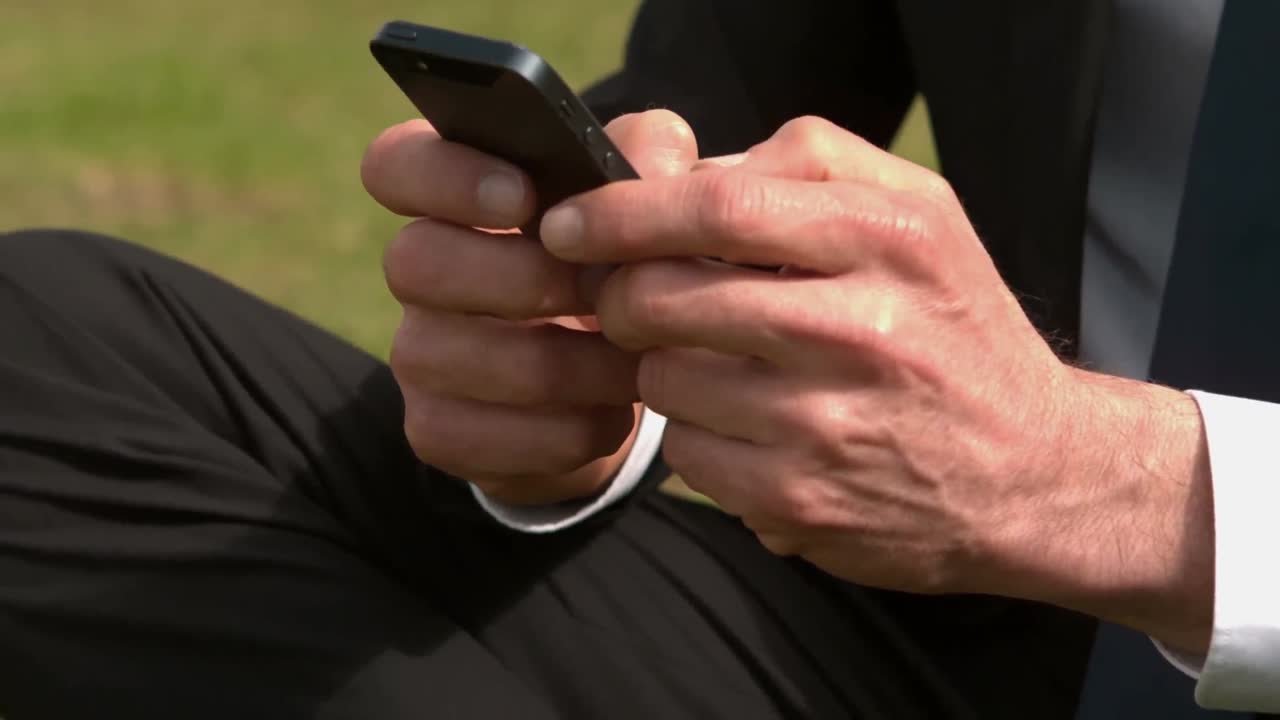 멋진 사업가가 스마트폰을 사용하고 있습니다.