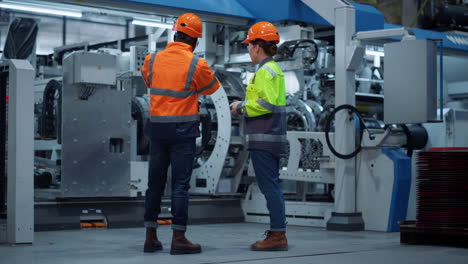 supervisores centrados trabajando en la fábrica de maquinaria moderna. hombres de negocios uniformados