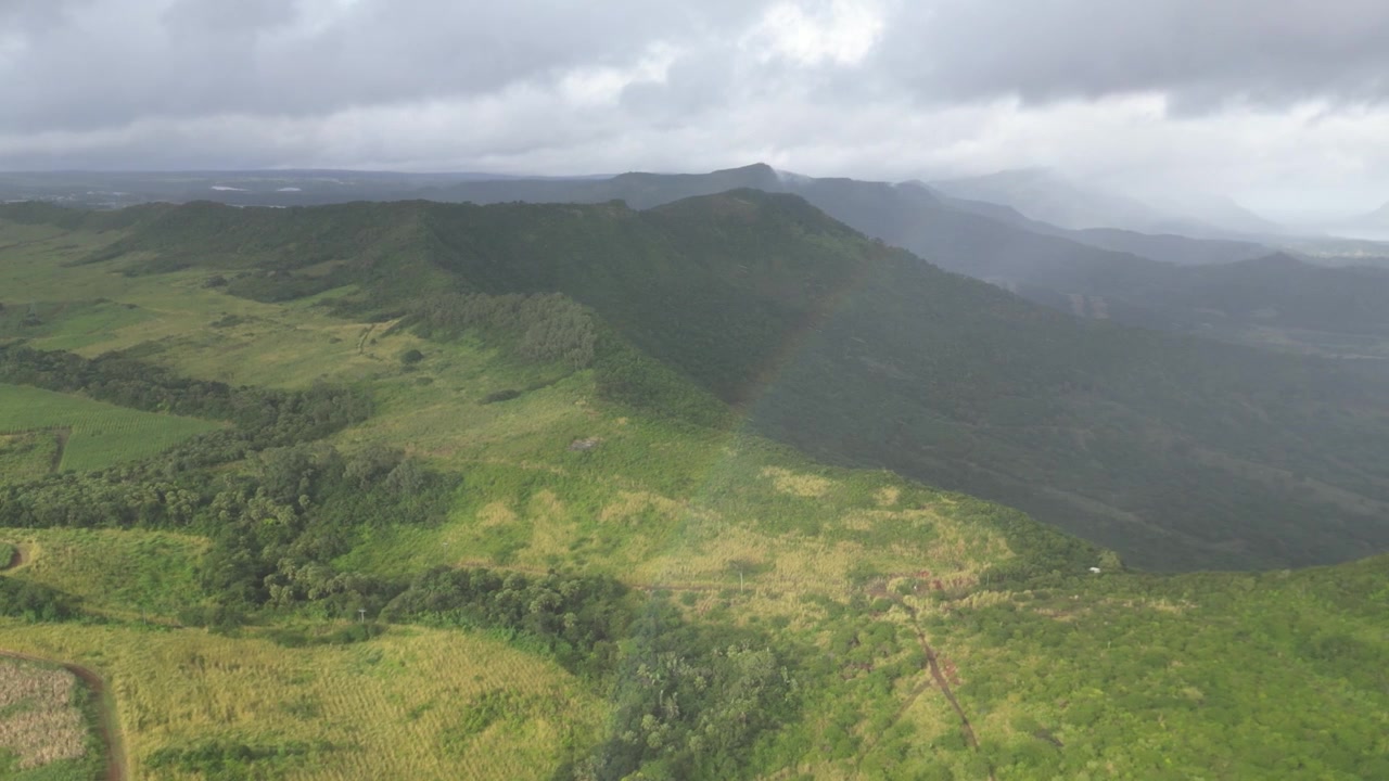 Pemandangan udara drone Montagne du Rempart dekat Flic en Flac, Mauritius. Lanskap pegunungan hijau subur dan topografi terjal di bawah langit berawan mendung. Panorama alam pulau tropis