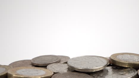 disparo macro de monedas británicas sucias cayendo sobre un fondo blanco