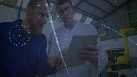 technician and engineer analyzing tablet in industrial plant, displaying data overlays, robotic arm