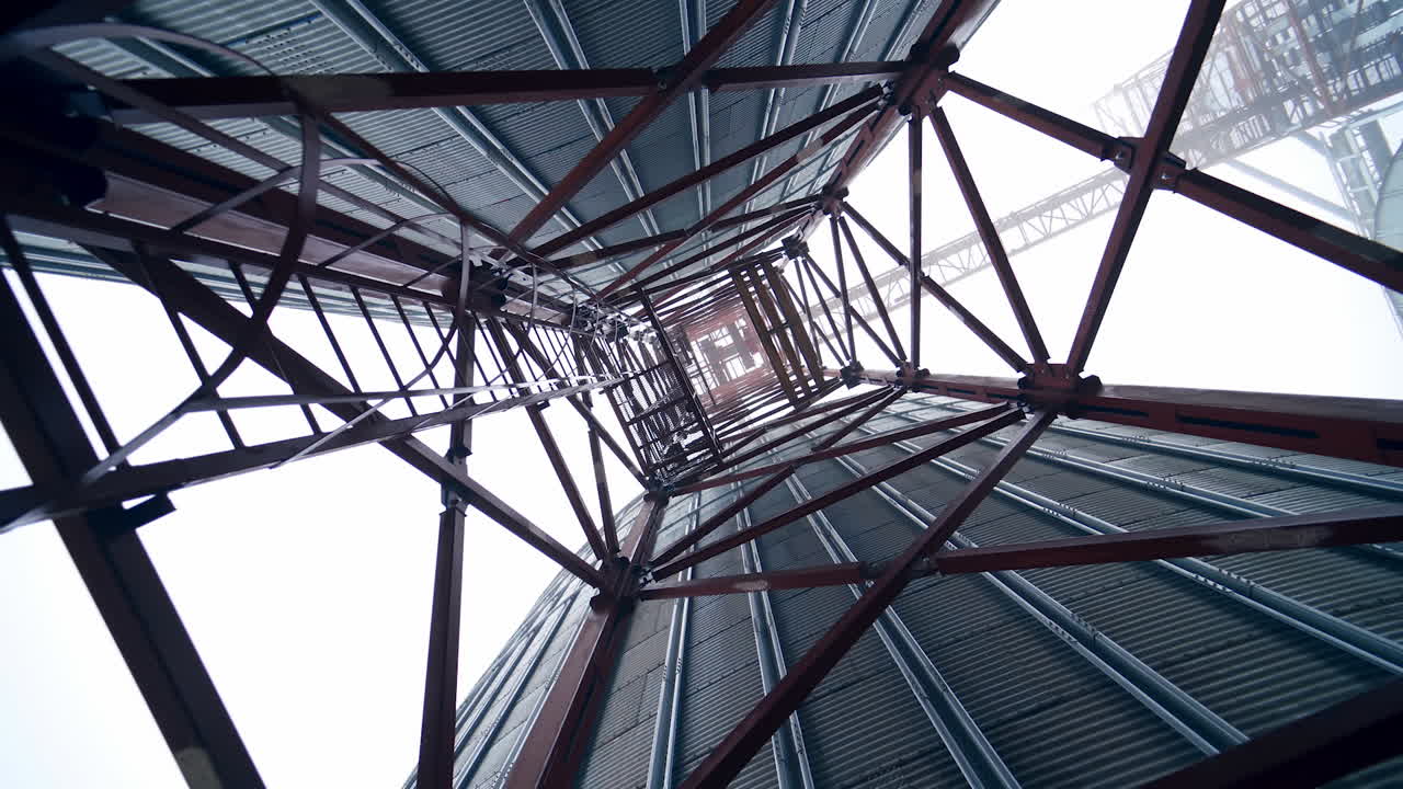 Metal towers on industrial plant.. Steel construction on a modern agricultural factory with grain elevators on sky background