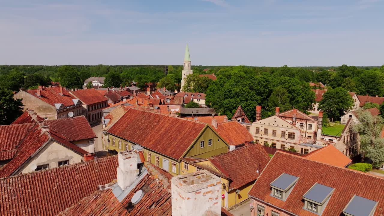 Establishing shot of Latvian heritage town Kuldiga with red roofs, church spire