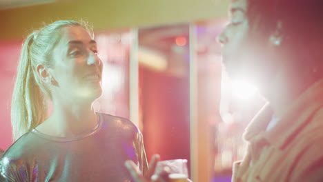 video of two diverse couples standing, drinking and talking at a nightclub