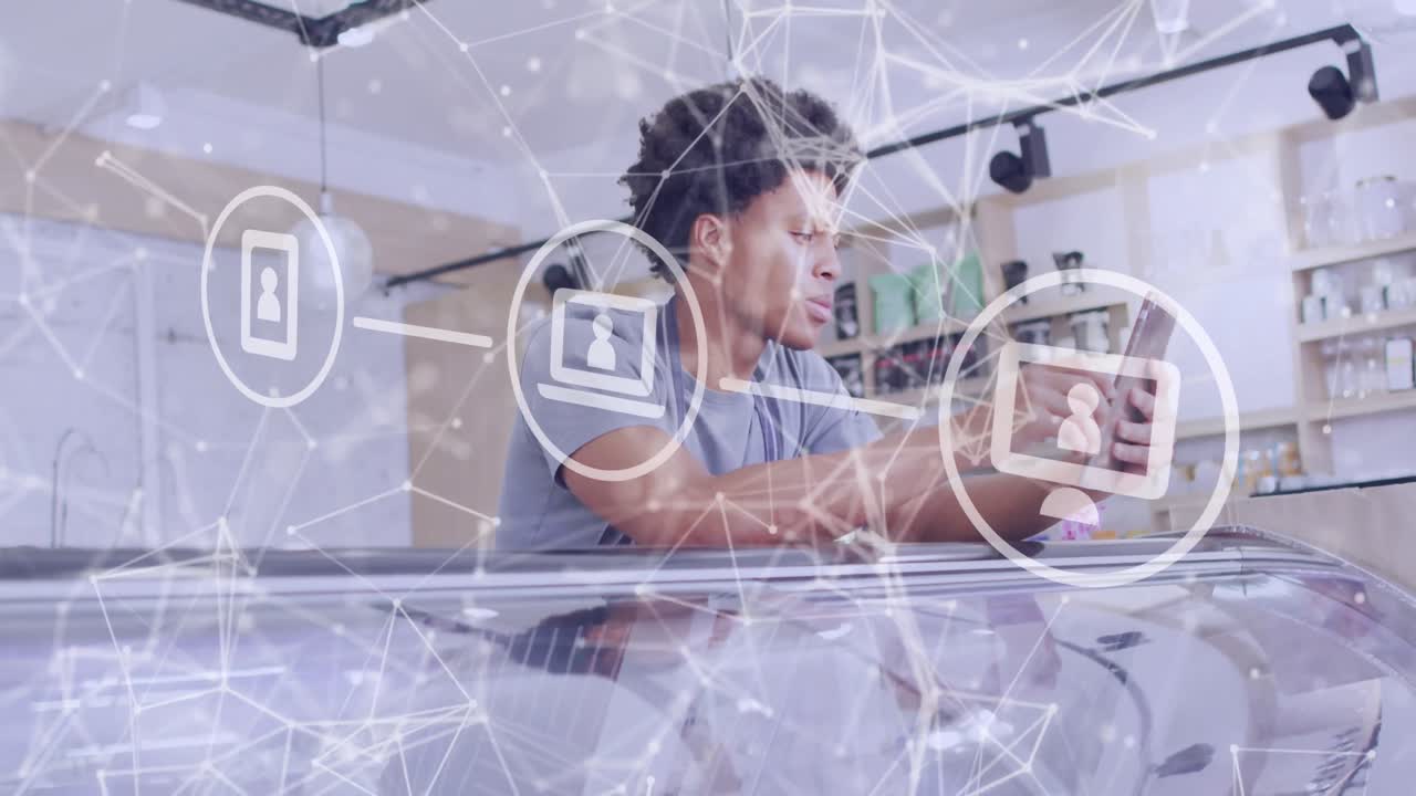 animación de iconos de los medios sobre asistente de tienda masculino biracial usando un teléfono inteligente.