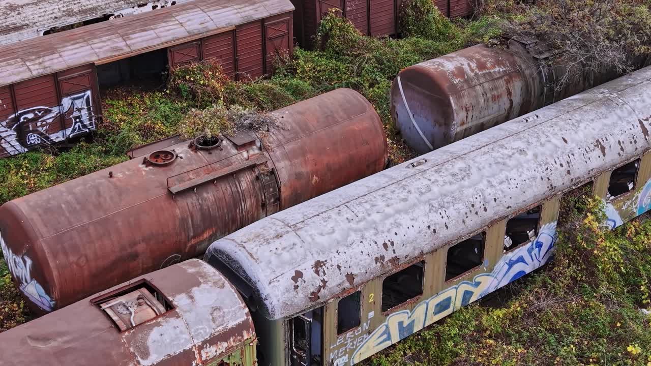 Forladte togvogne dækket af graffiti i Grækenland nær tilgroede skinner