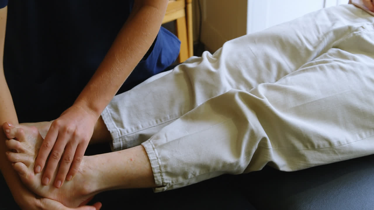 fisioterapeuta dando terapia de piernas a una mujer mayor 4k