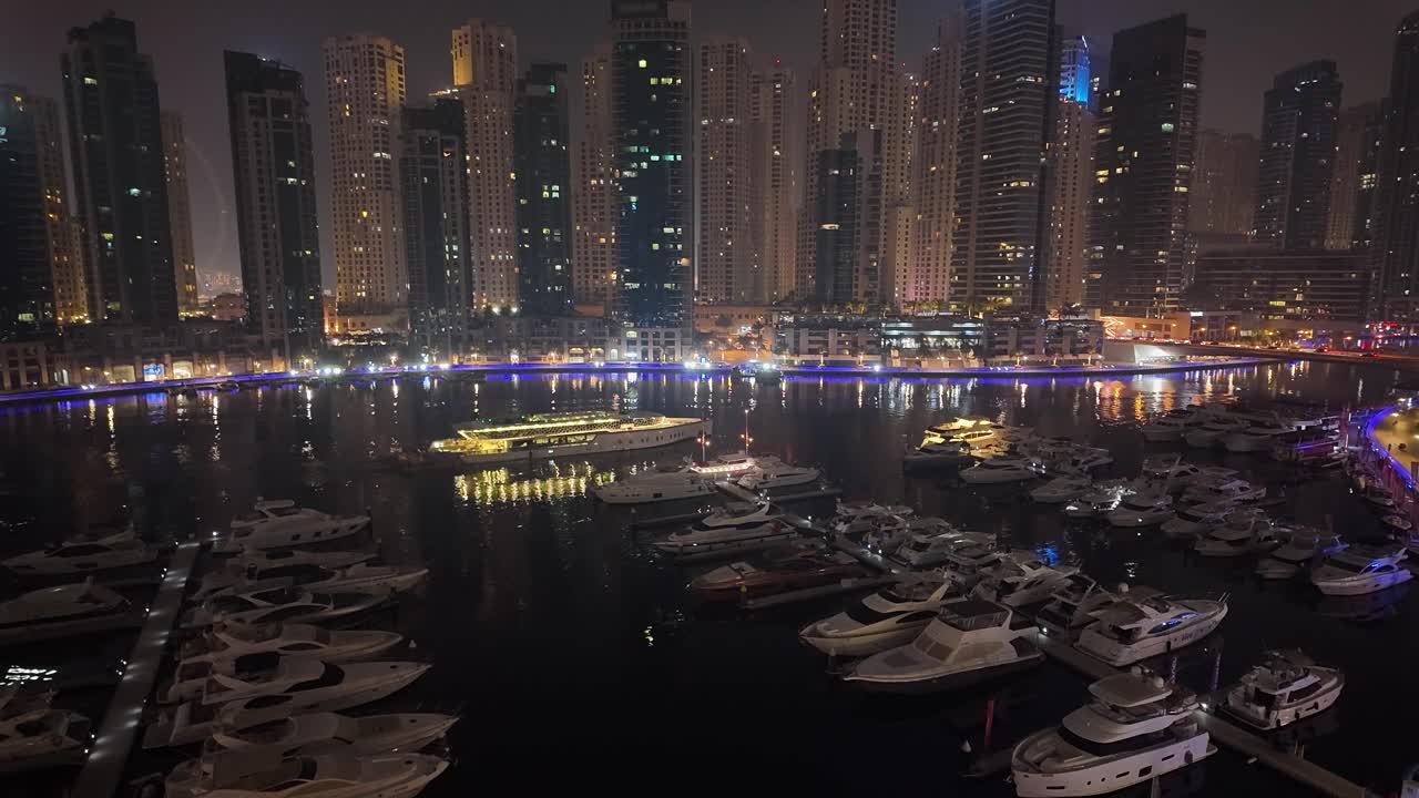 Paysage nocturne de Dubaï Marina avec un navire passant devant des gratte-ciel et des yachts