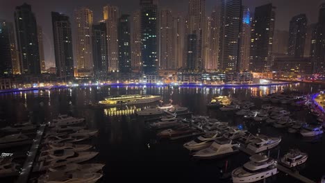 dubai marina nightscape with ship cruising past skyscrapers and yachts