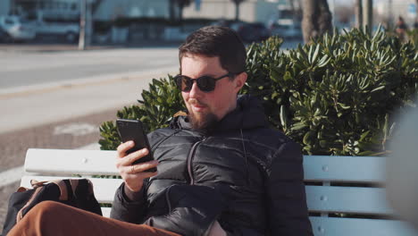 hombre usando un teléfono inteligente en un banco del parque