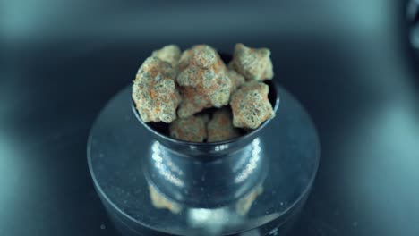 un zoom cinematográfico en detalle del movimiento suave de la grúa de una planta de cannabis, cepas híbridas de naranja, tipo indica, flor de marihuana verde, cámara lenta 120 fps, luces de estudio, soporte giratorio brillante