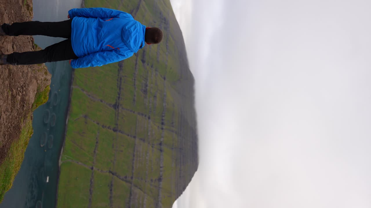 Man reaching the top of Klakkur Mountain and stops at the cliff's edge