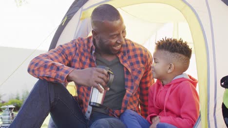 Glücklicher-Afroamerikanischer-Vater-Und-Sein-Sohn-Sitzen-Im-Zelt-Und-Reden-Im-Garten