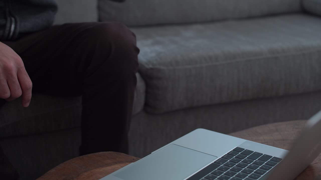 Close up man typing on laptop then drinks from his mug at home
