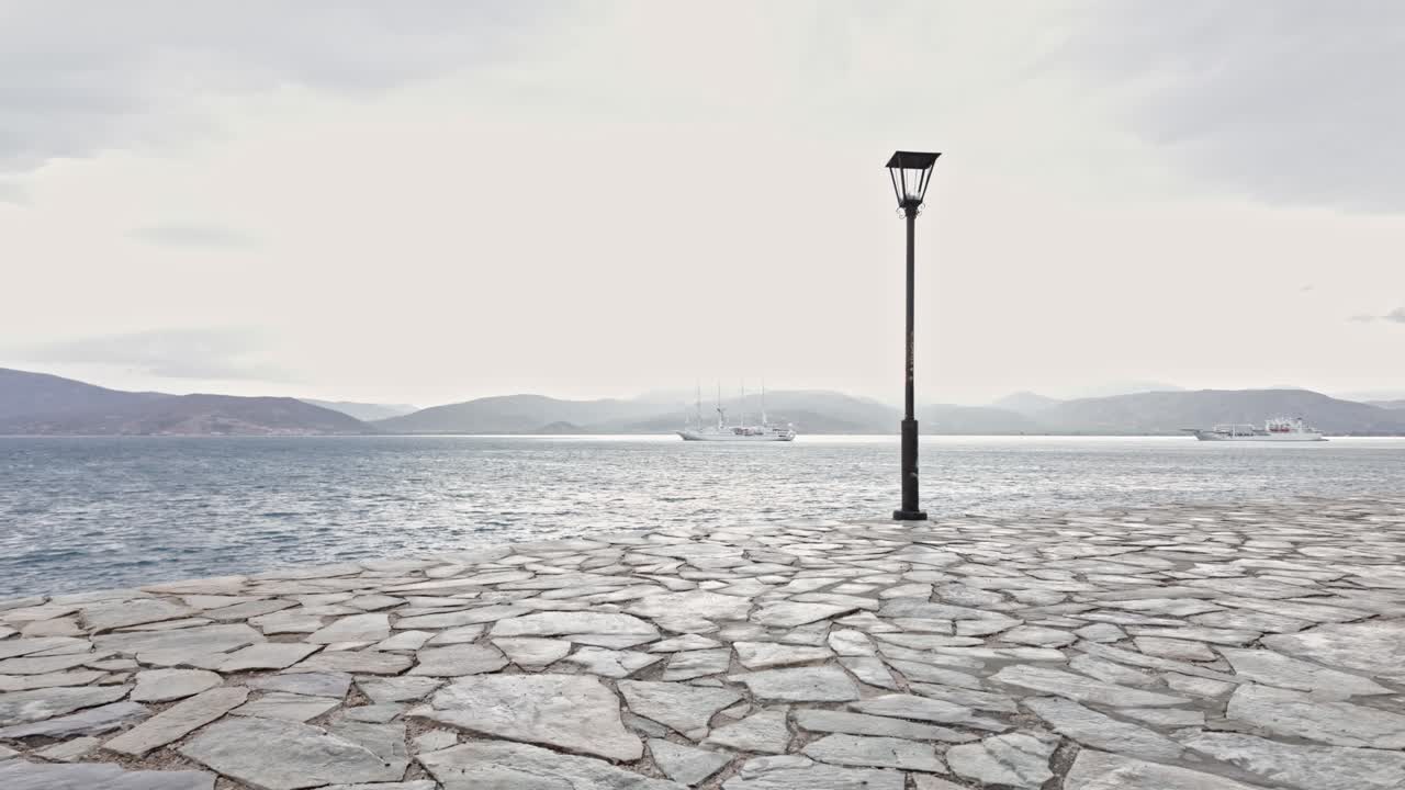 Distant tourist cruise ships anchored off Greek Bouritz bay coastal path Nafplion