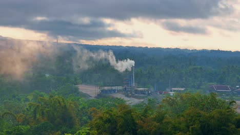 smoking factory chimney in natural landscape of indonesia, aerial view