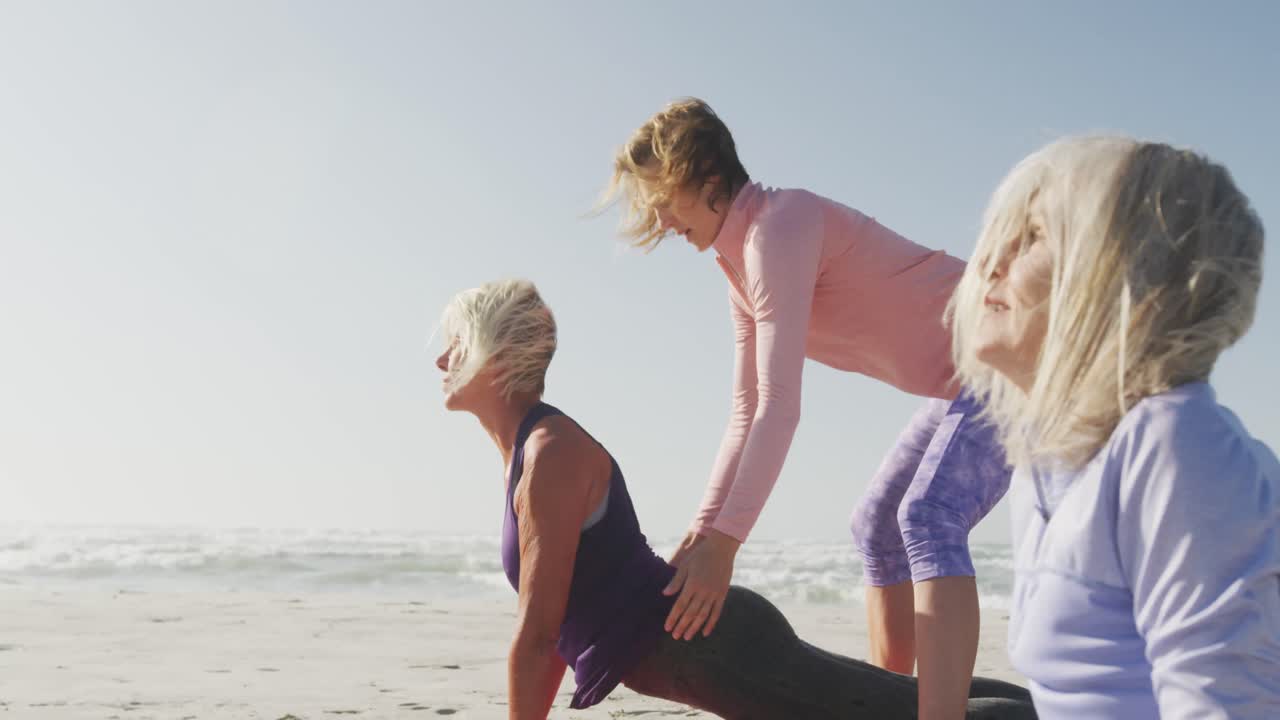 Yoga teacher teaching yoga to senior  women at the beach