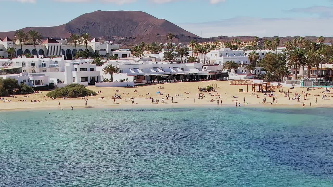 Windsurfisti scivolano sull'acqua vicino a una spiaggia alle Canarie