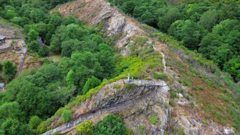 rocky trail atop lush green forest in a cortevella, lugo, galicia, spain, aerial view