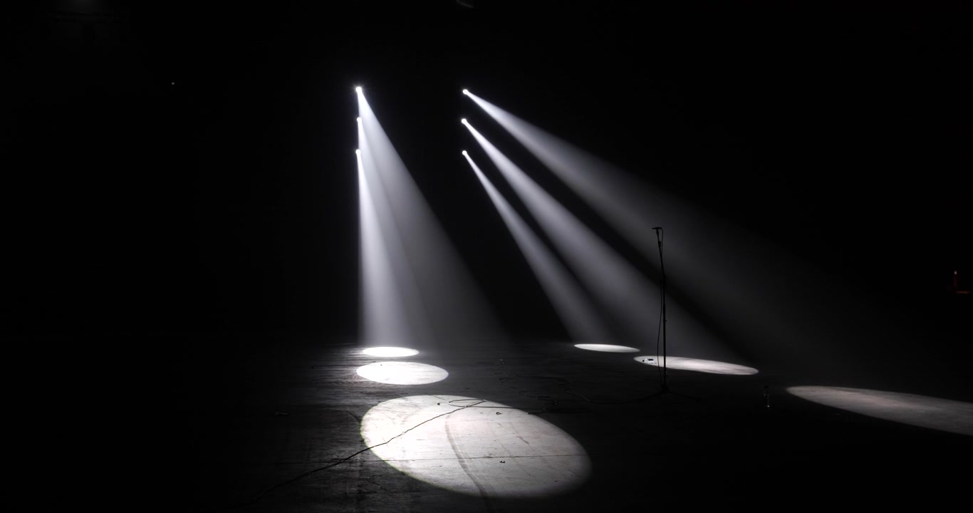Luces de escenario parpadeantes crean una atmósfera intensa en un entorno oscuro.