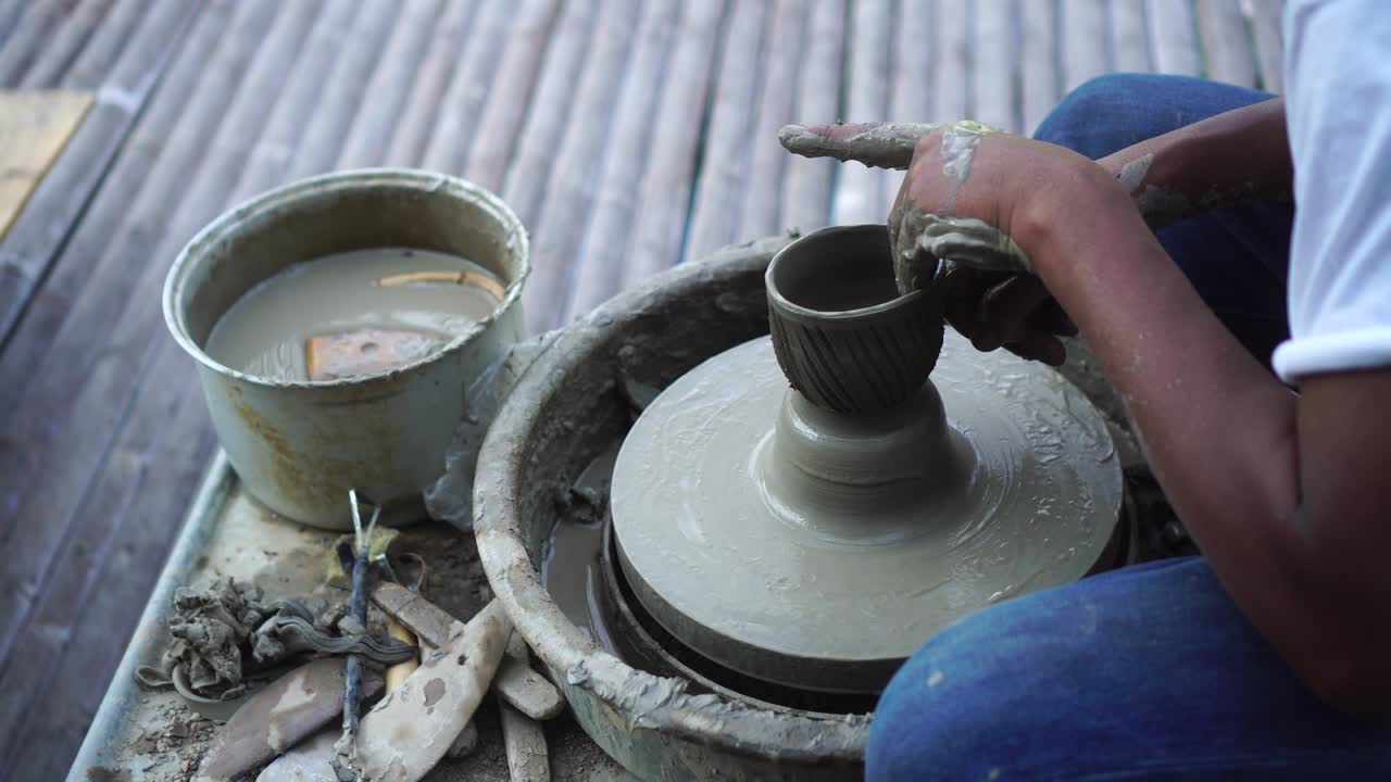 도자기의 바에서 점토를 작업하는 손의 근접. 도자기는 도자기의 에서 도자기 도구로 점토 제품을 형성합니다.
