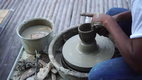 cerca de las manos que trabajan la arcilla en la rueda del alfarero. el alfarero da forma al producto de arcilla con herramientas de cerámica en la ruedas del alfarer, vista superior, cinematográfica tonada, auténtica fábrica de artesanía