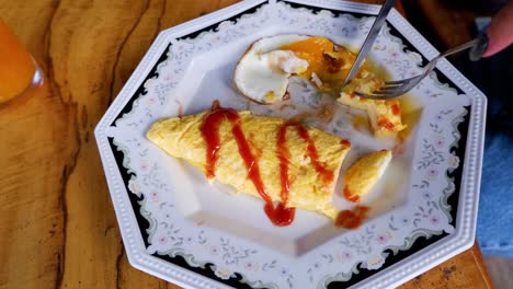 person enjoying omelet with sauce and drink