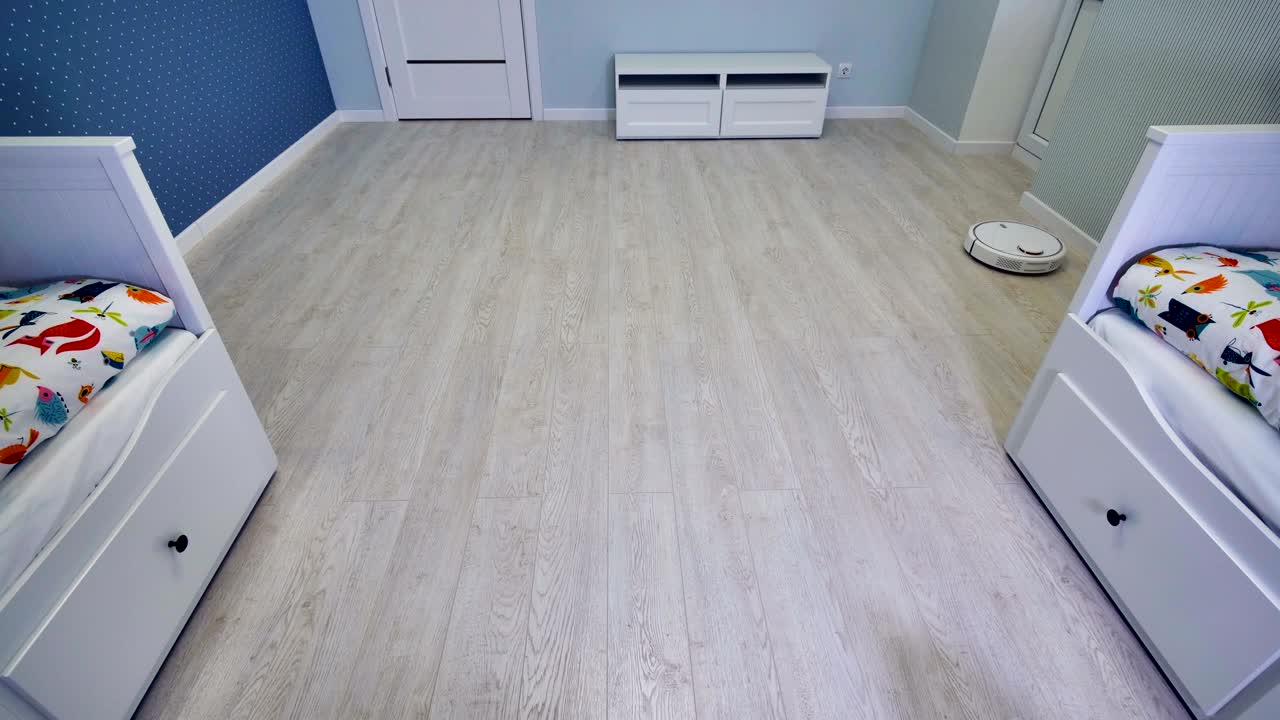 una habitación infantil medio vacía limpiada rápidamente por una aspiradora robótica.