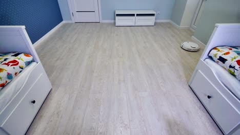 una habitación infantil medio vacía limpiada rápidamente por una aspiradora robótica.