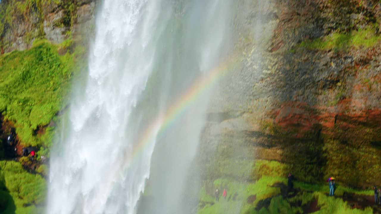 fuerte corriente de agua que cae de la cascada seljalandsfoss con vistas a un arco iris en islandia