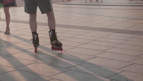 slow mo, person rollerblading on beach boardwalk during golden hour between crowd