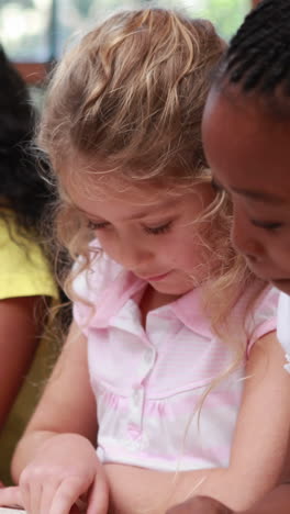 video vertical de chicas caucásicas y afroamericanas leyendo juntas en la escuela