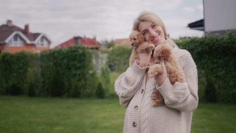 portrait of a pregnant woman with puppies in her hands, standing in the backyard of the house