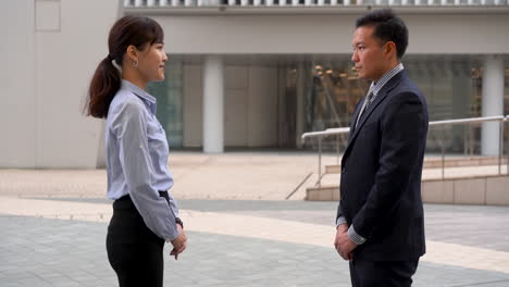 japaneses business man and woman greet each other with bow. respect and formality.