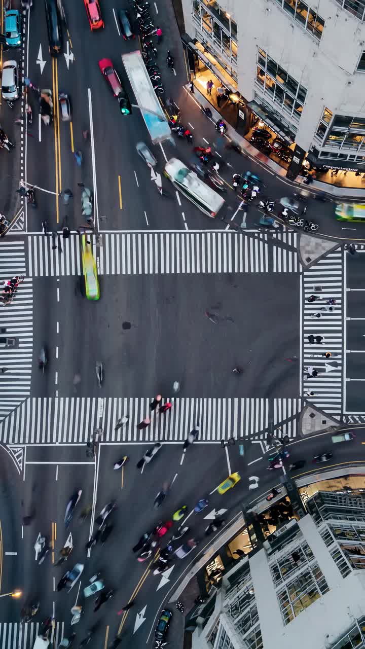 Aerial view of a bustling city intersection with moving cars and pedestrians, capturing urban life