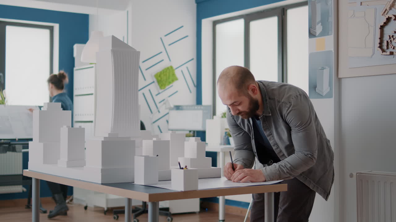 Architects working on building model and blueprints in office