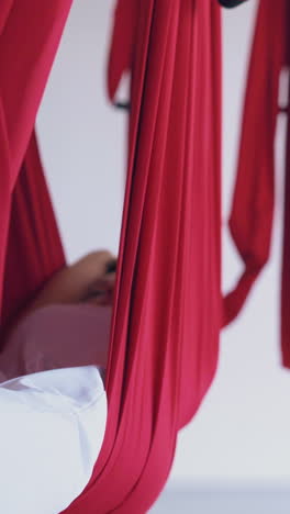 women lie and relax after modern fly yoga in special hammocks in pilates studio extreme close view