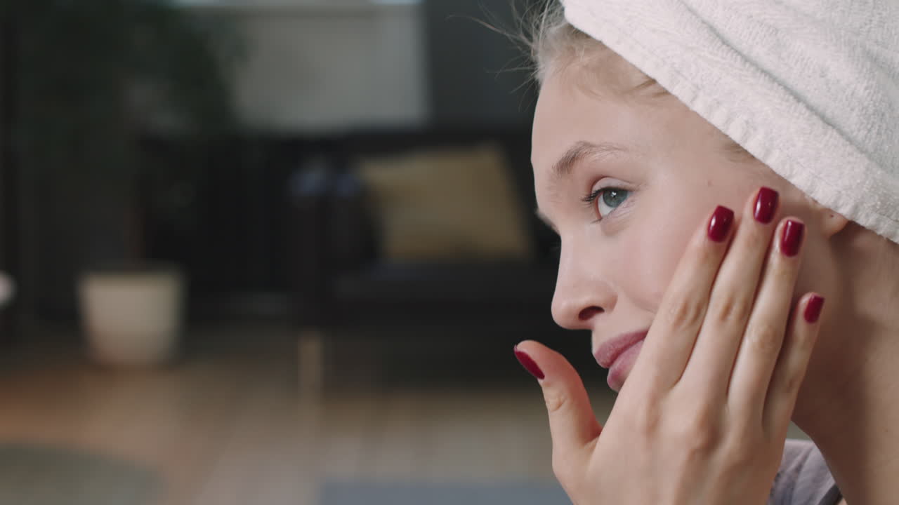Giovane donna sorridente che applica crema sul viso