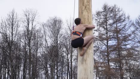 man climbing a wooden pole