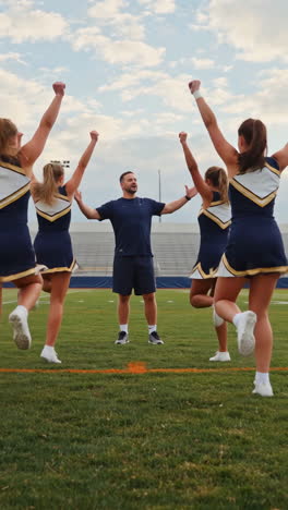 cheerleaders and coach practicing on a football field