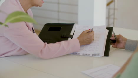 unrecognizable female real estate agent showing document and talking with clients