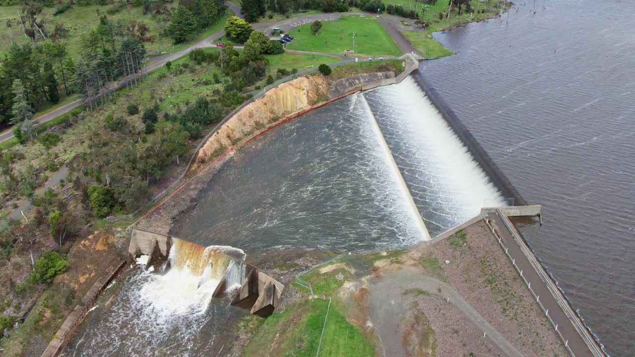 Moving up and away aerial view of water spilling over the Upper Coliban Reservoir spillway, central Victoria, Australia. October, 2022.