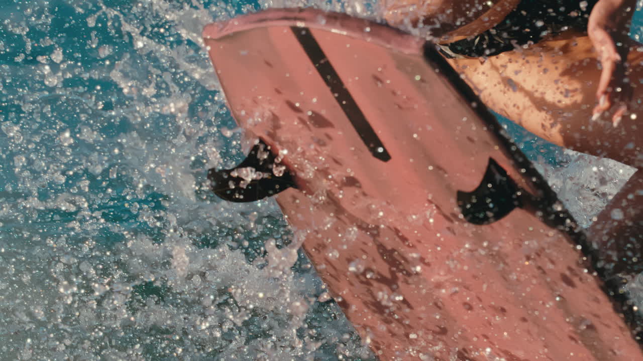 close up de la tabla de surfista de vigilia femenina aterrizando un truco con gotas de agua en todas partes en cámara lenta extrema