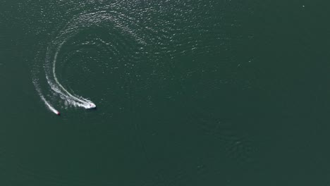 Aerial-view-of-a-boat-pulling-a-tube-at-high-speed-on-a-Dutch-lake