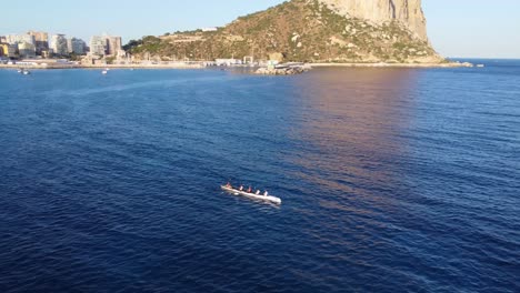 an athletic sports team on a rowing boat sail out to sea on the coast of spain