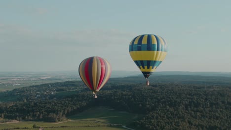 4k aerial hot air balloons getting close to each other above forest