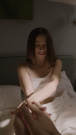young woman smiling and reaching out in bed