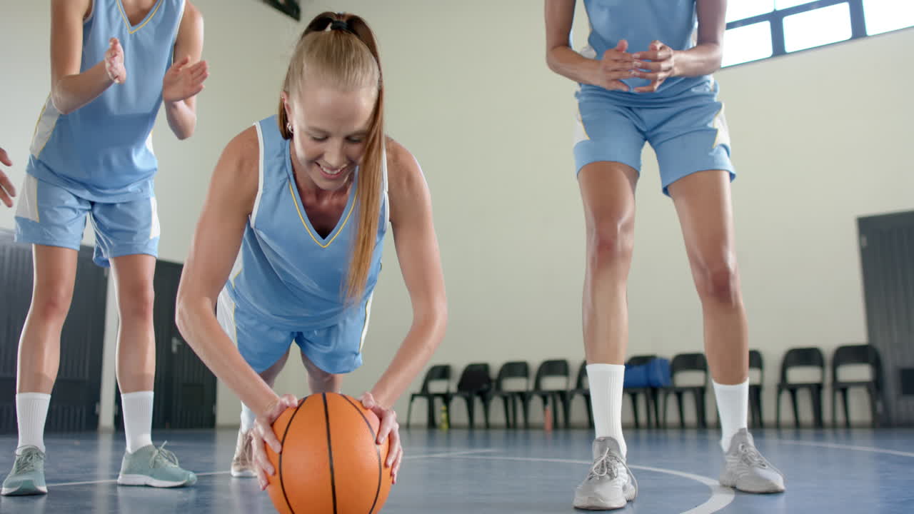 Exercising with basketball, female basketball player doing push-ups in gym