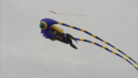 three colourful kites dance together in the wind at a kite festival