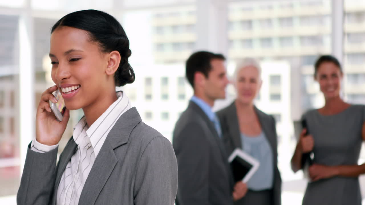 Businesswoman having a phone call with colleague in background